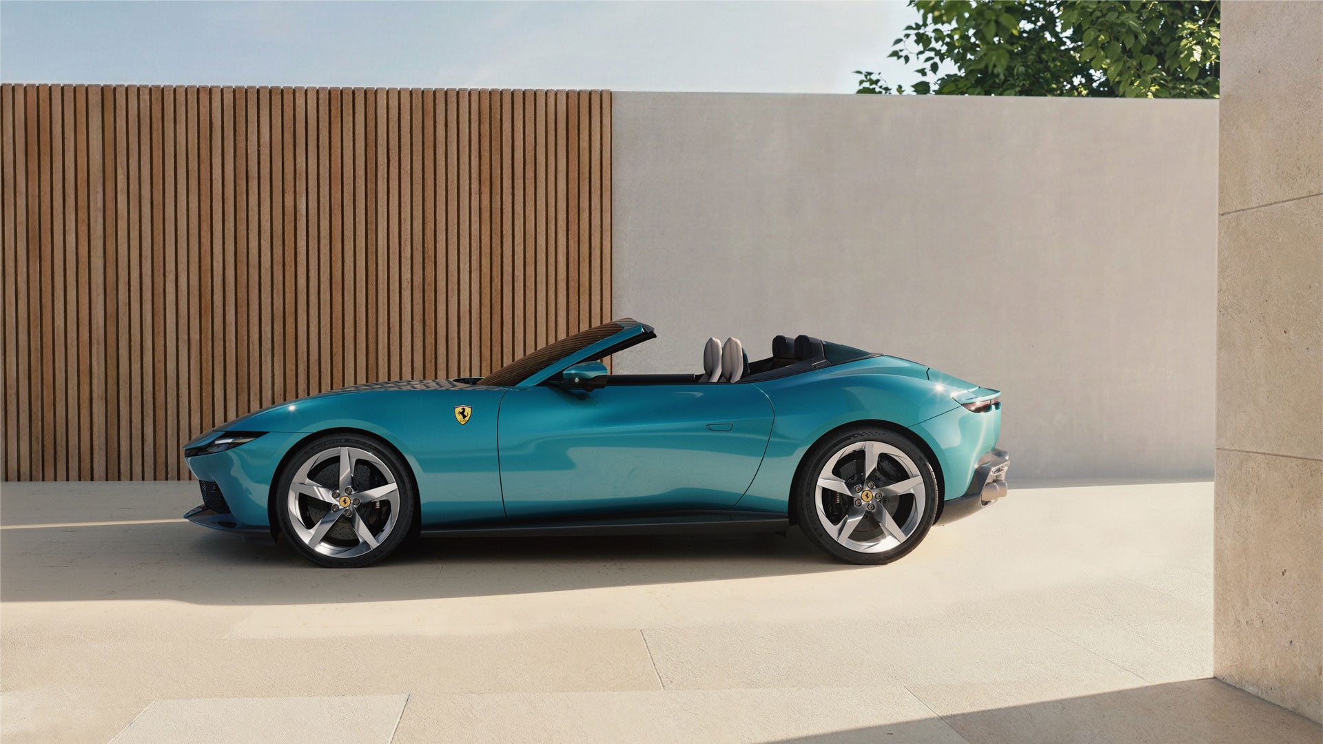 Top-down view of a light gray Ferrari with two white stripes extending from front to back, on asphalt.