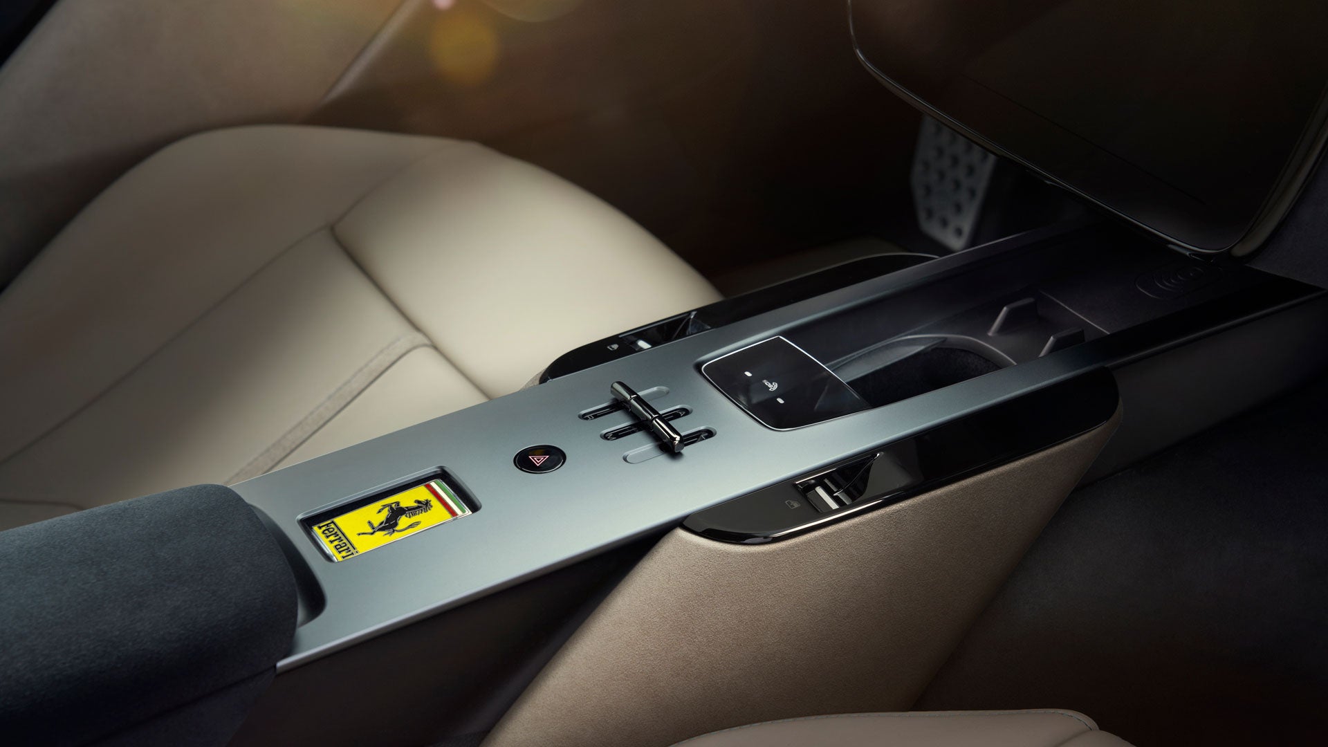 The interior of a car, showing a light gray console with controls, a Ferrari emblem, and beige leather seats.