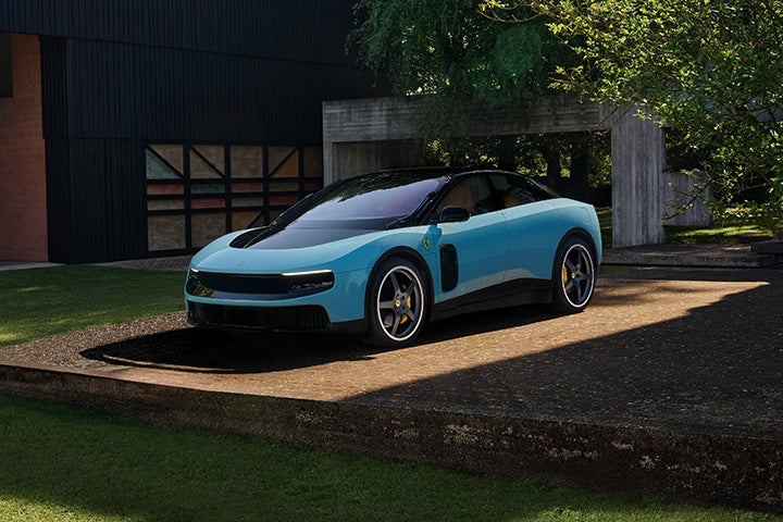 A sleek, light blue Ferrari Purosangue parked on a concrete driveway in front of a modern house.