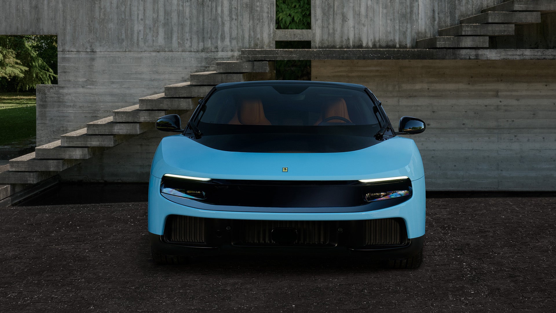 Front view of a sleek, light-blue car with a black roof and interior, parked before concrete stairs.